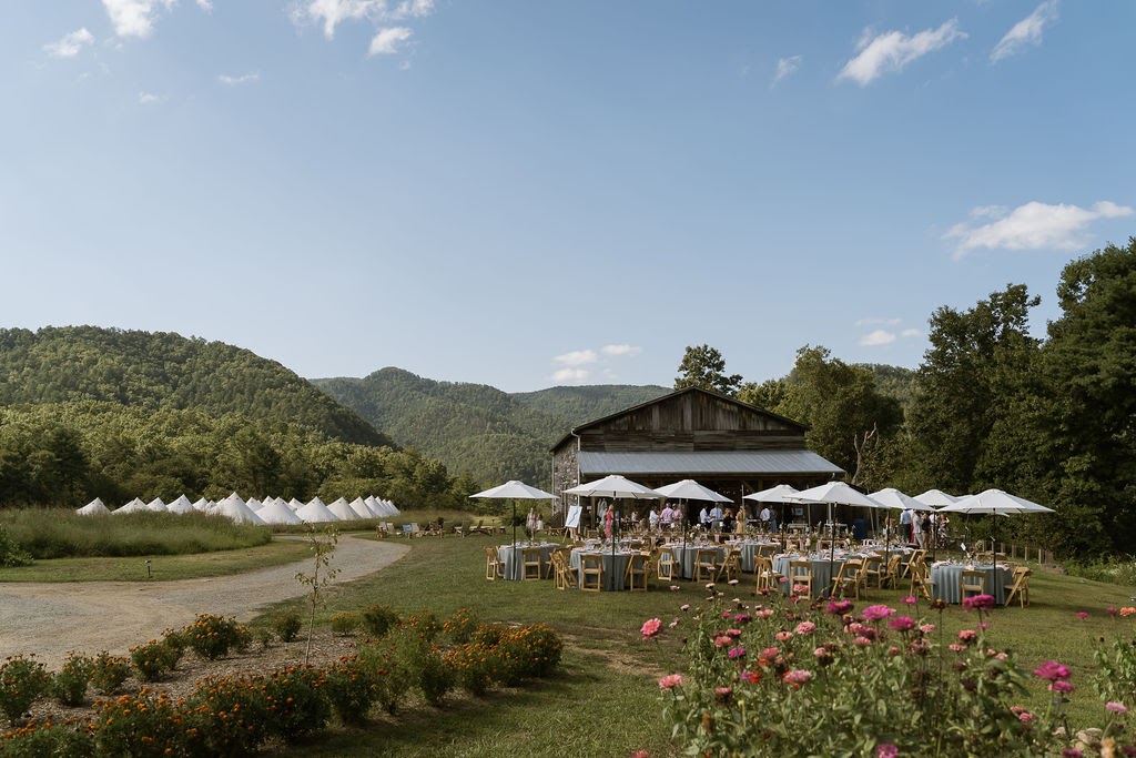 wedding reception at a barn in the mountains with tents set up for guests to stay in off in the distance. 