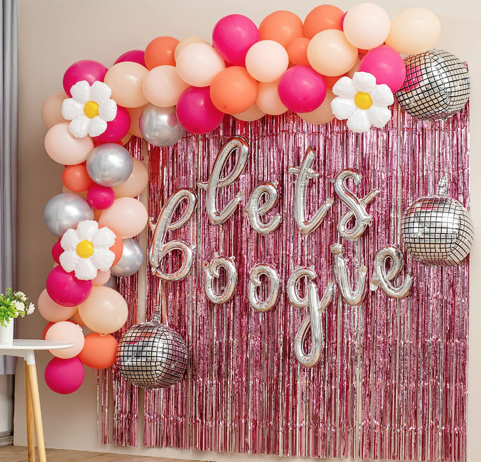 large photo backdrop with a multicolor balloon arch and balloons that say "let's boogie"