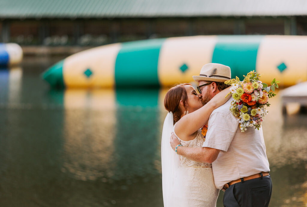 couple kissing on their wedding day in front of a lake