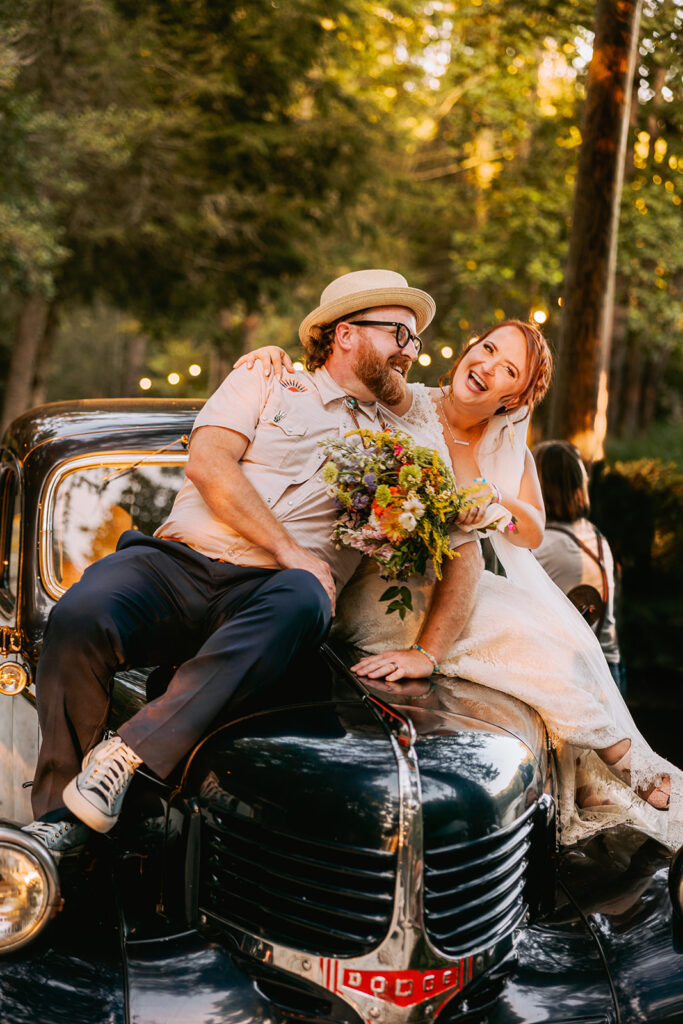 bride and groom sitting on vintage truck at their wedding